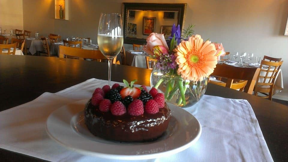 A white linen table with champagne and a chocolate and berry dessert at Du Venti in Downtown Clawson