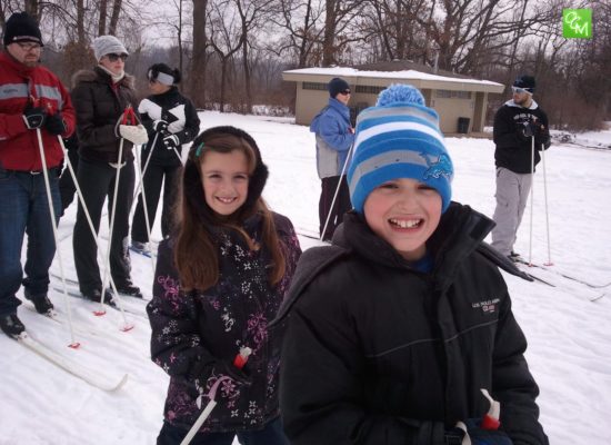 Two young children and family getting ready to cross country ski at one of the Oakland County parks.